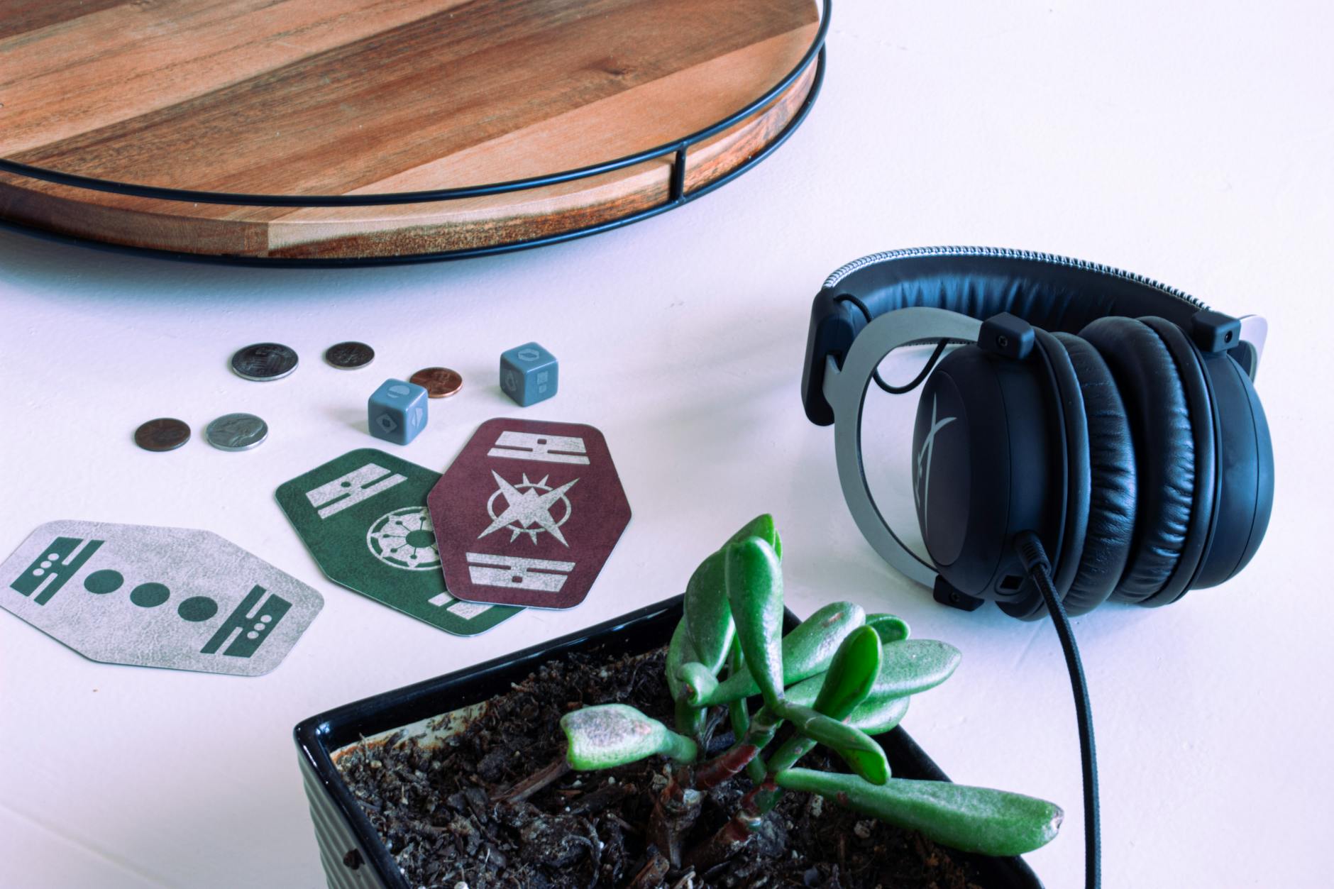 Artistic close-up of headphones, playing cards, coins, and a succulent plant on a wooden tray.