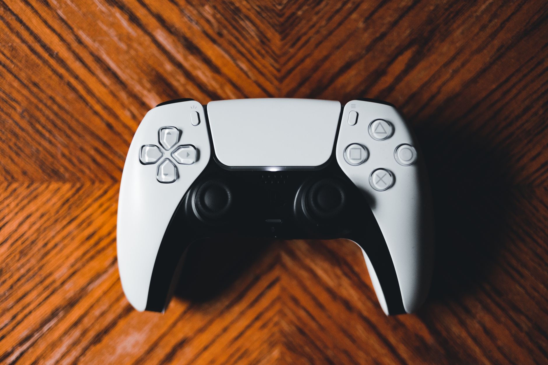 A detailed shot of a modern game controller on a richly textured wooden surface.