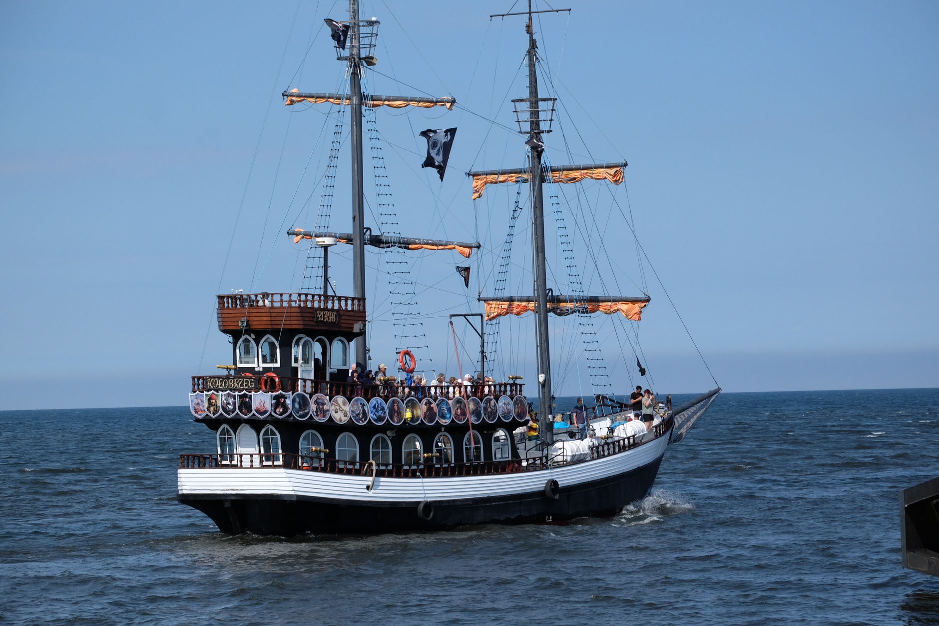 Pirate ship cruising on the ocean under a clear blue sky, showcasing adventure.