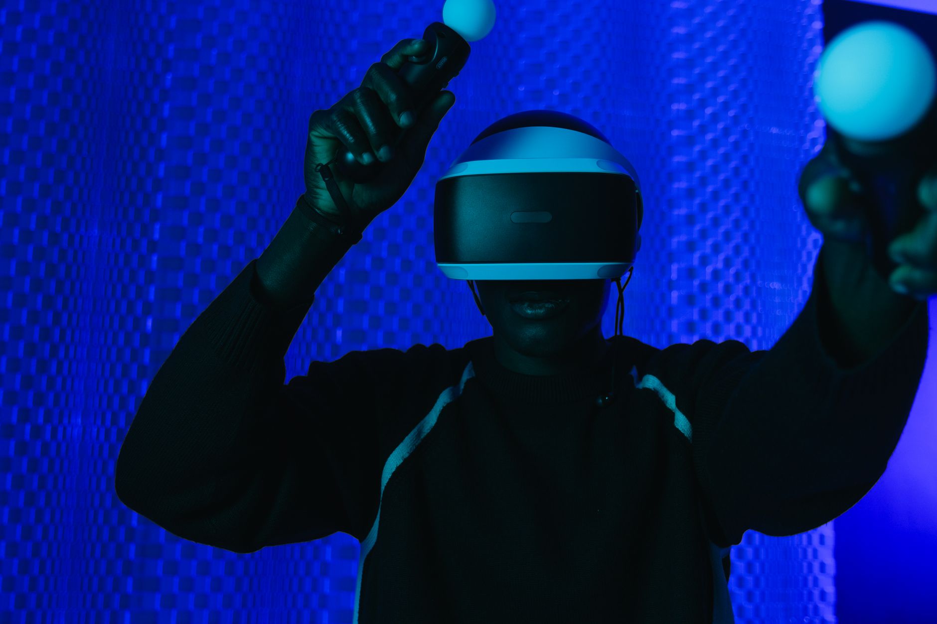 Person enjoying a virtual reality gaming session with a VR headset and controllers.