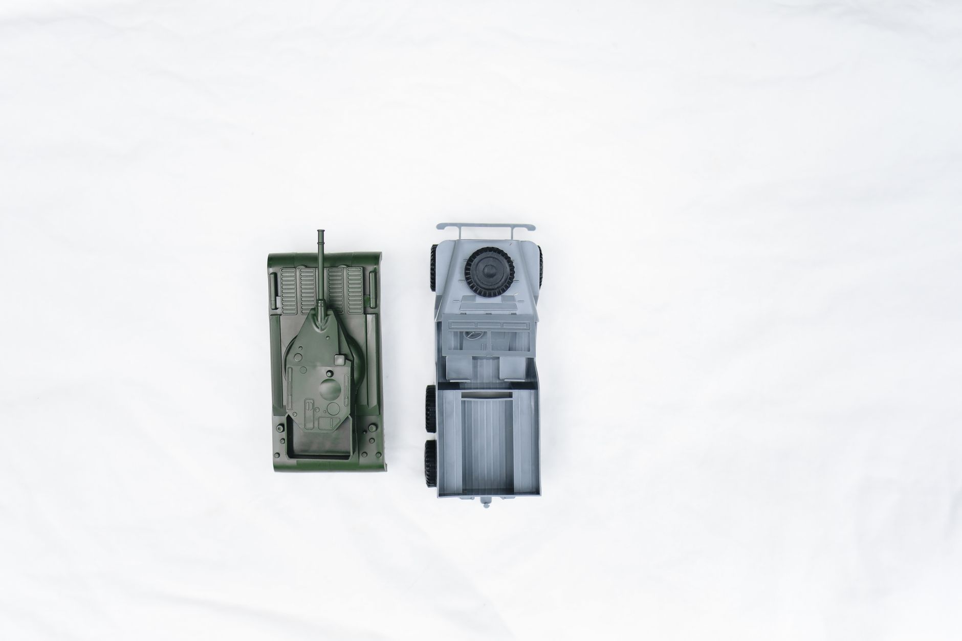 Two toy vehicles, a tank and a jeep, viewed from above on a white background.