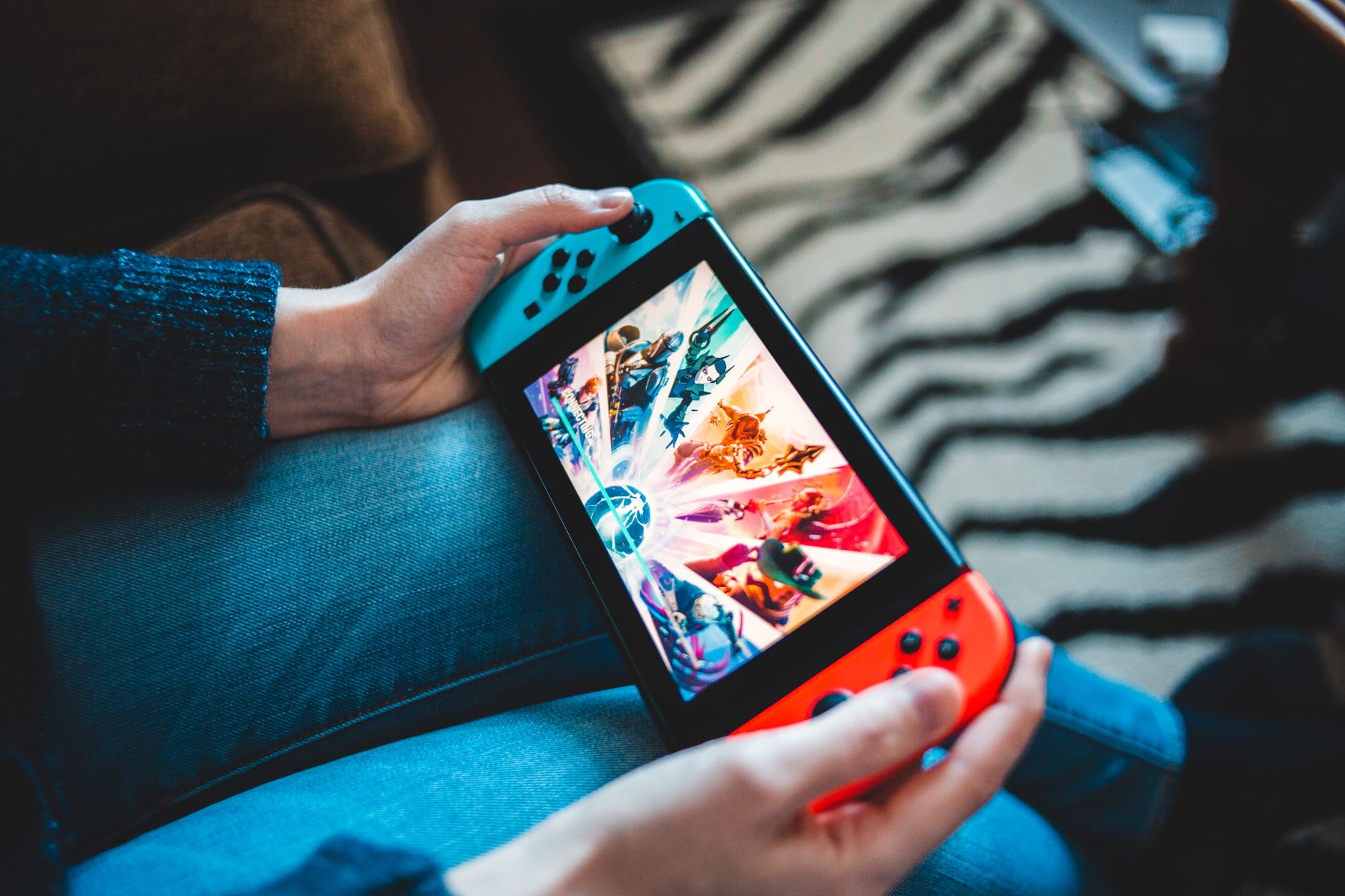 Person gaming on a handheld Nintendo Switch console with blurred background.