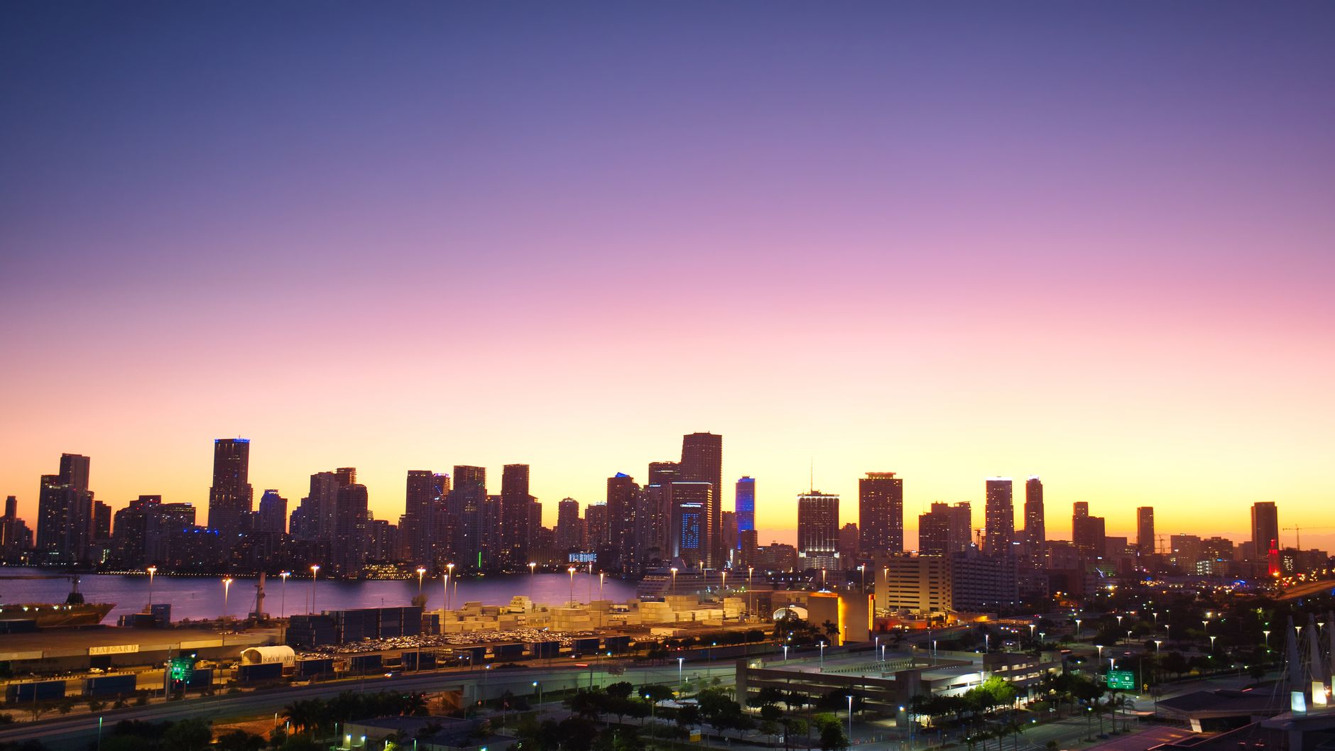 Aerial view of Miami's skyline at twilight with vibrant sunset colors casting a warm glow.