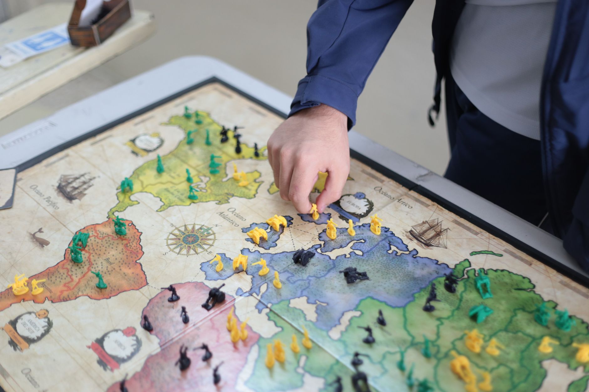 Close-up of a hand playing a strategic board game on a colorful map.