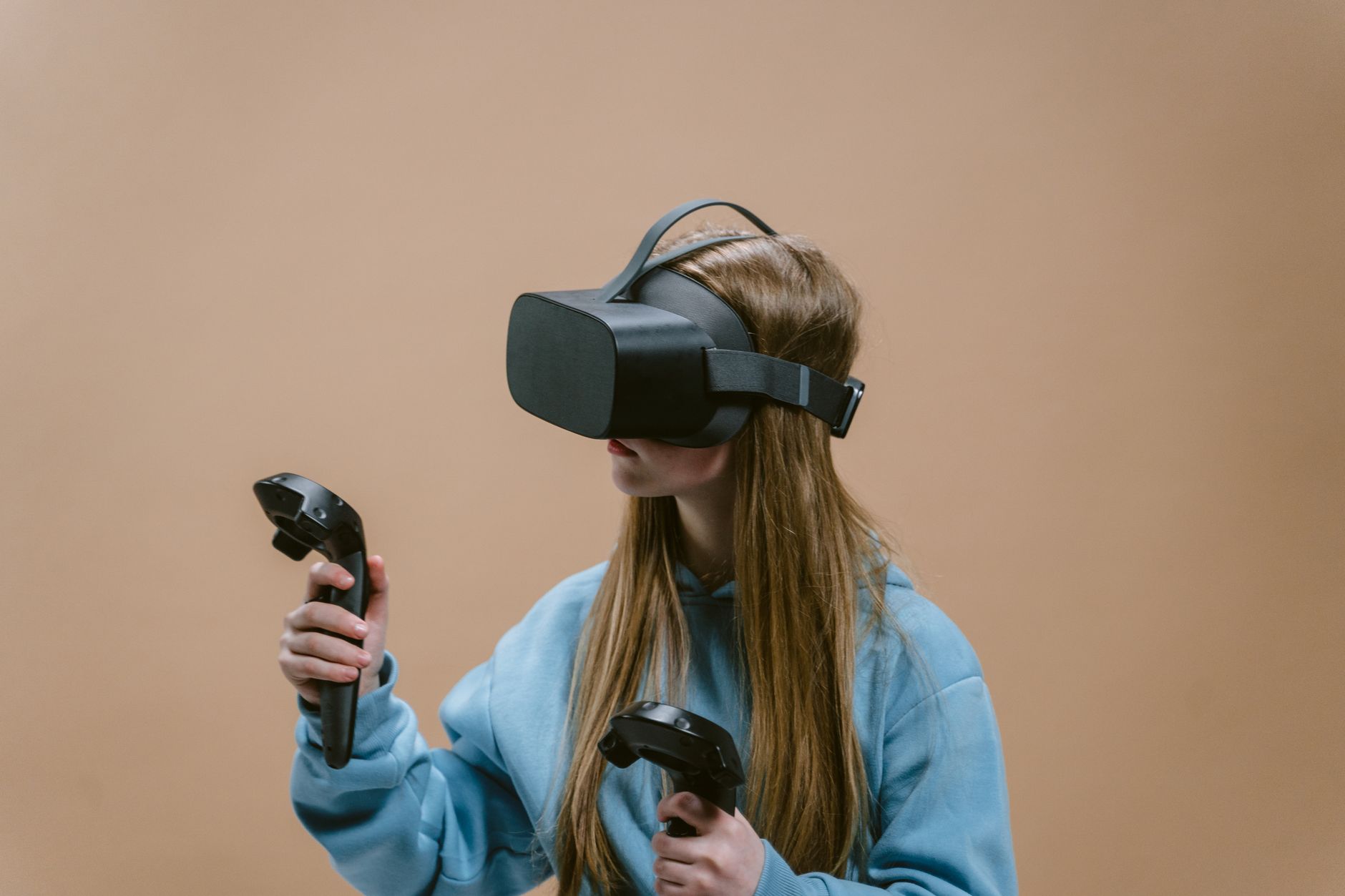 Woman using a VR headset and controllers, immersed in virtual reality gaming experience.