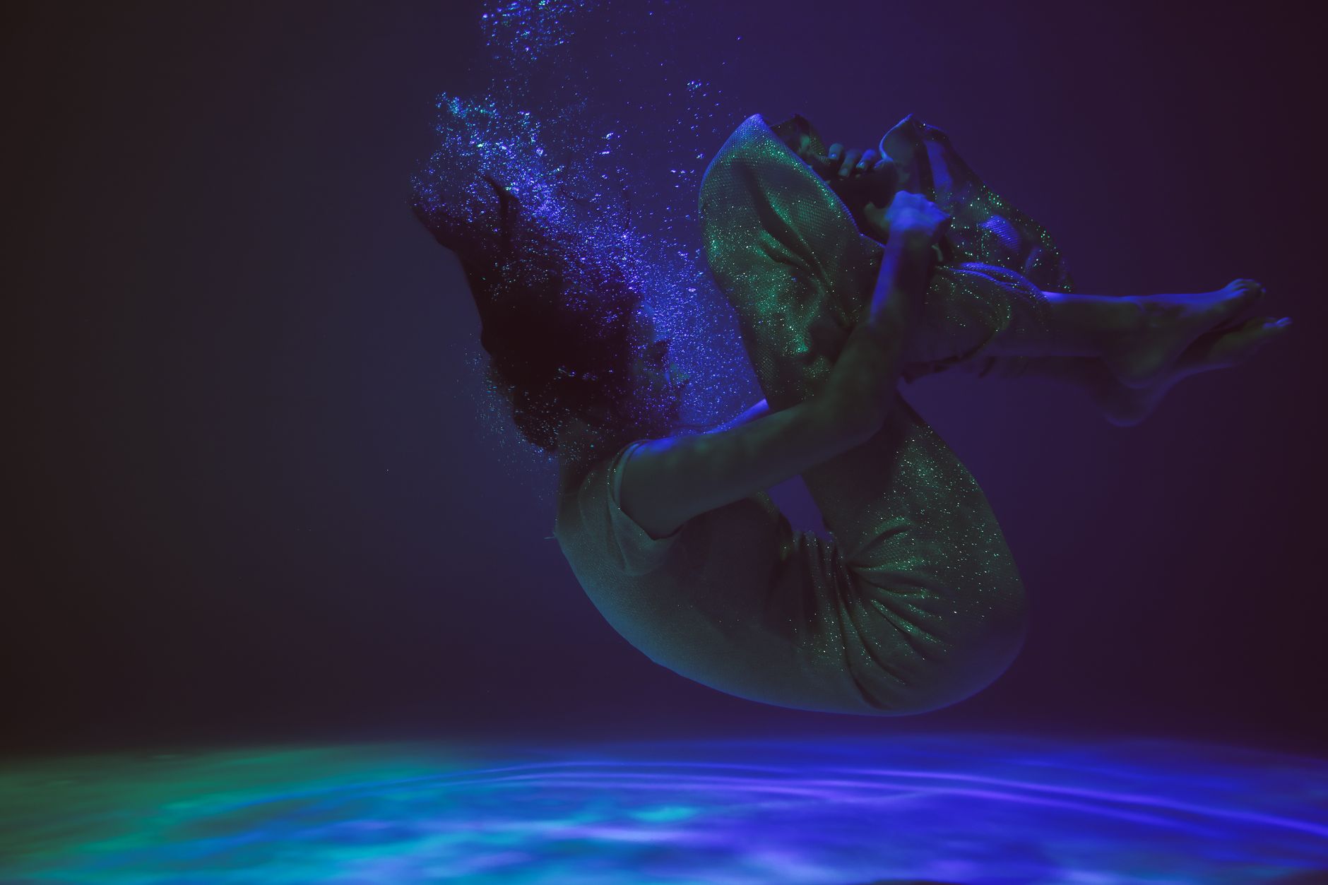 Artistic underwater photo of a person floating gracefully in deep blue water. Captivating and serene.