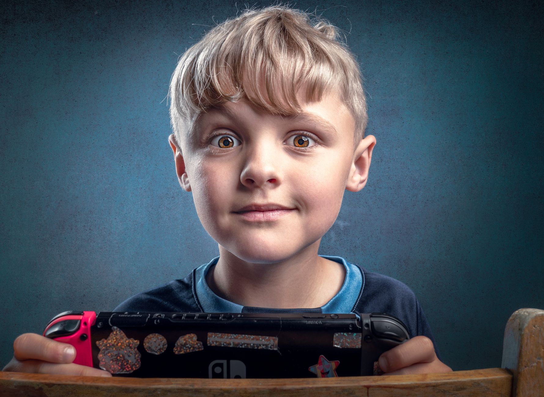 A young boy playing with a game console, showcasing joy and concentration in a portrait setting.