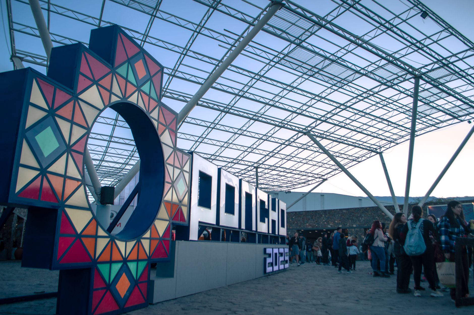 Vibrant signage at a bustling indoor expo event with attendees gathering and colorful lighting.