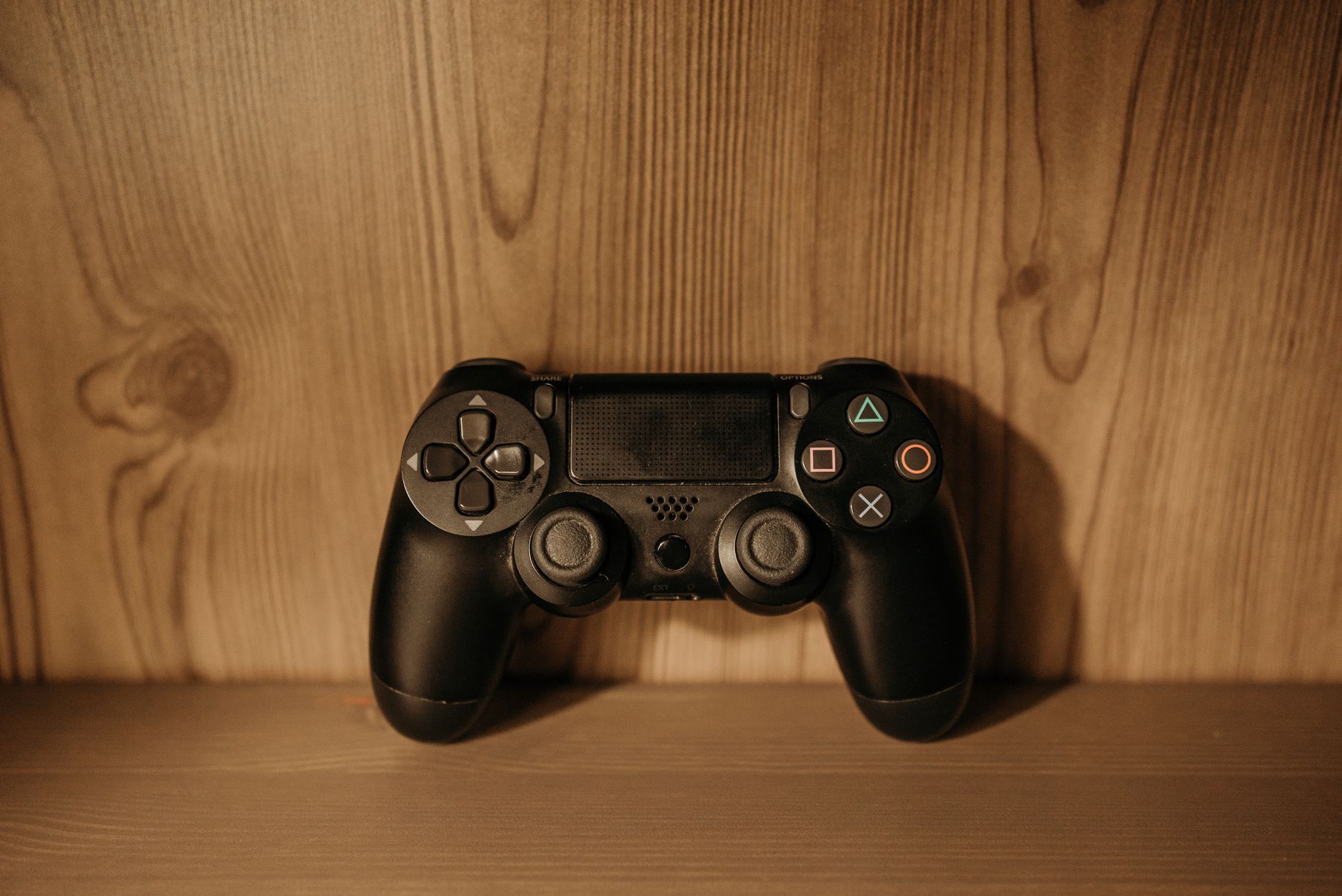Close-up view of a black PlayStation controller placed on a wooden surface.