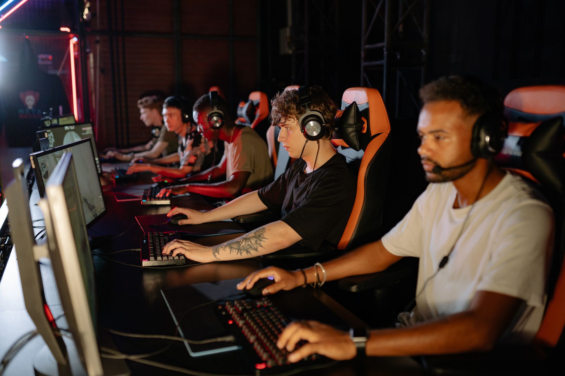 A group of focused young gamers playing in an intense esports tournament indoors.