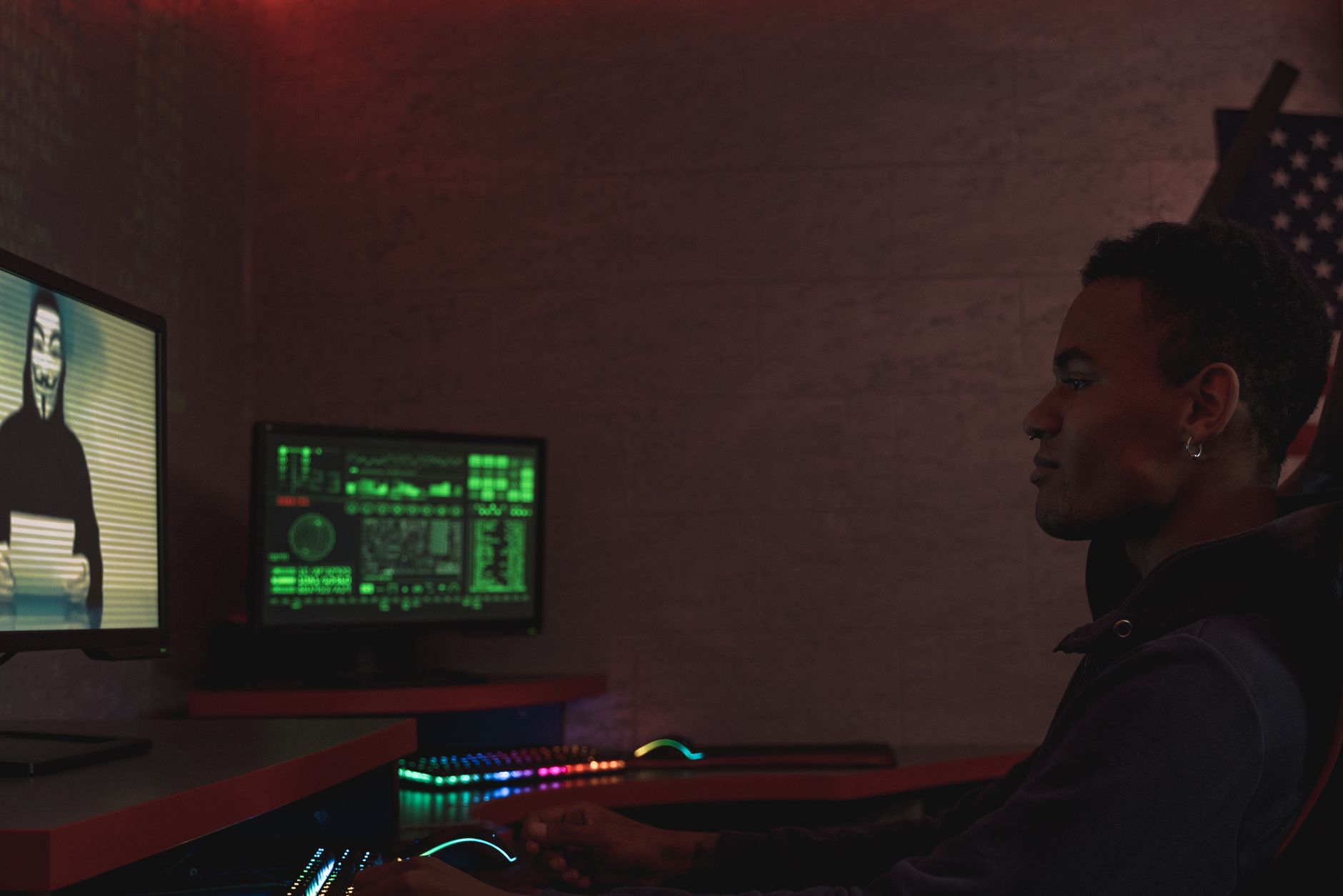 A cybersecurity professional monitors data systems in a dark room, emphasizing protection and vigilance.