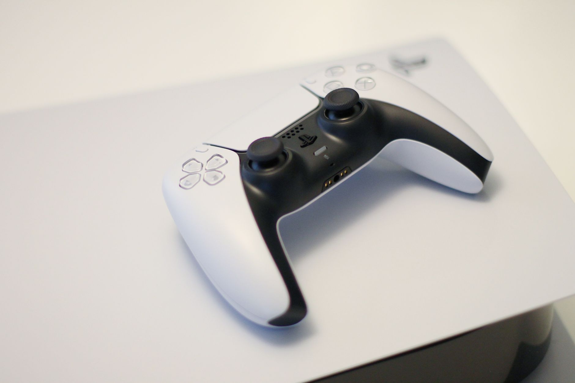 White and black game controller resting on top of a matching console.