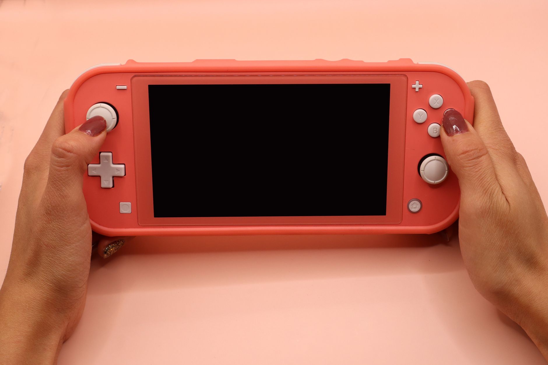 Close-up of hands holding a pink Nintendo Switch Lite, perfect for gaming or tech visuals.
