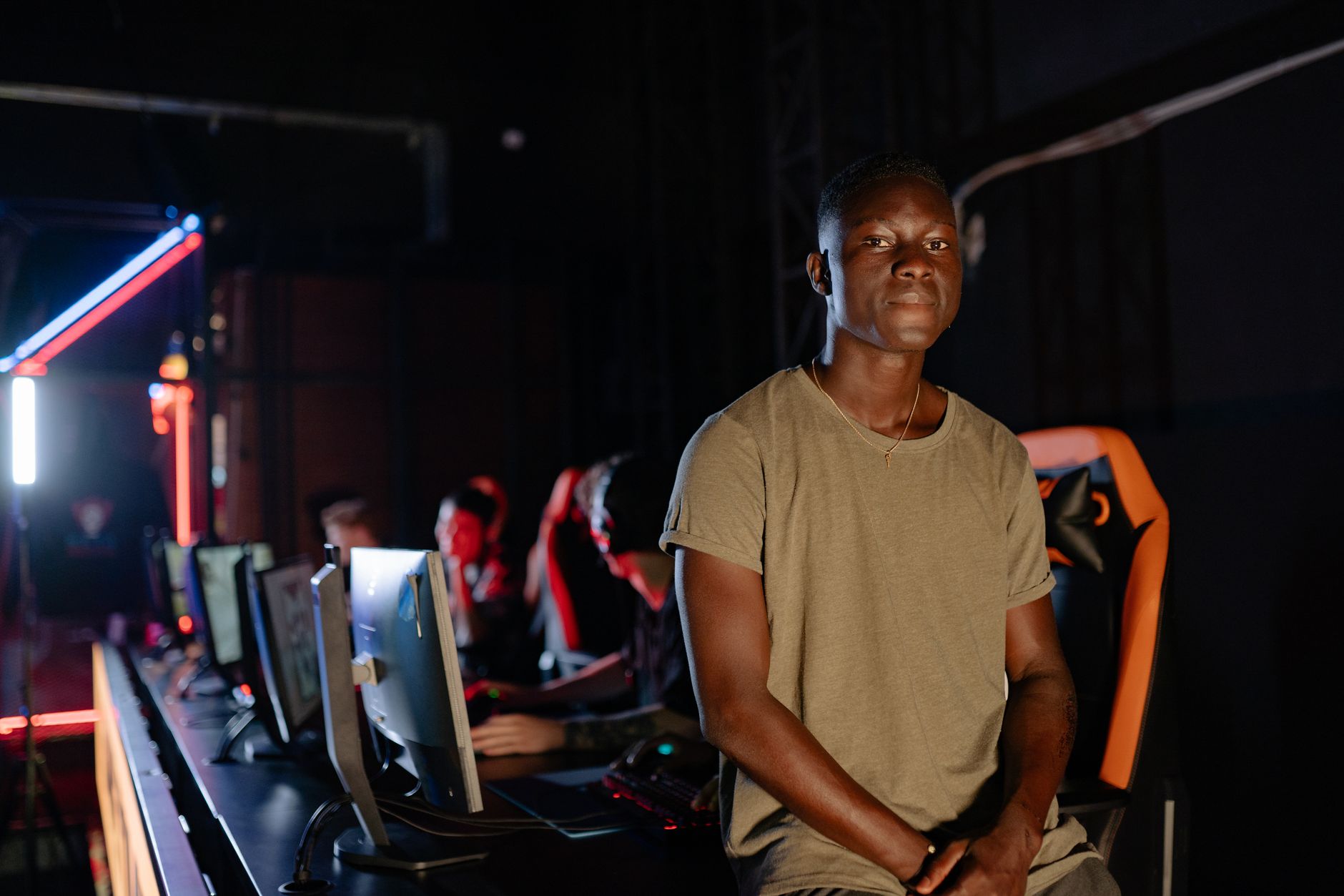 A young gamer in a dimly lit gaming arena, surrounded by teammates.