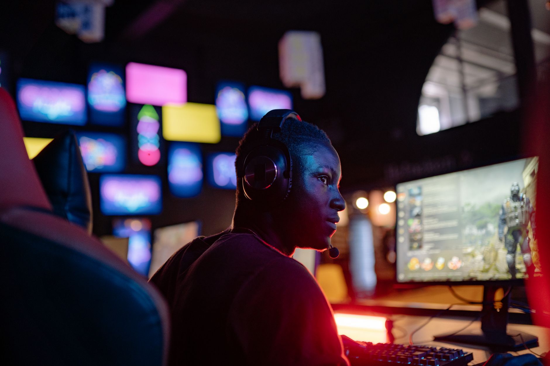 A young man intensely focused on a gaming session at a colorful gaming setup, wearing headphones.