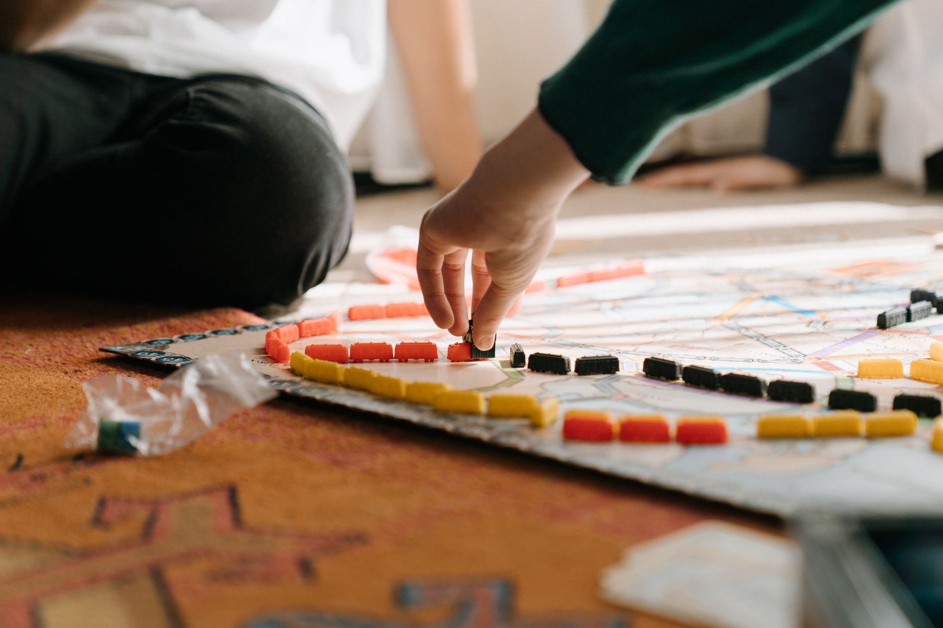 People playing a strategic board game indoors, focusing on hand placing pieces during leisure time.