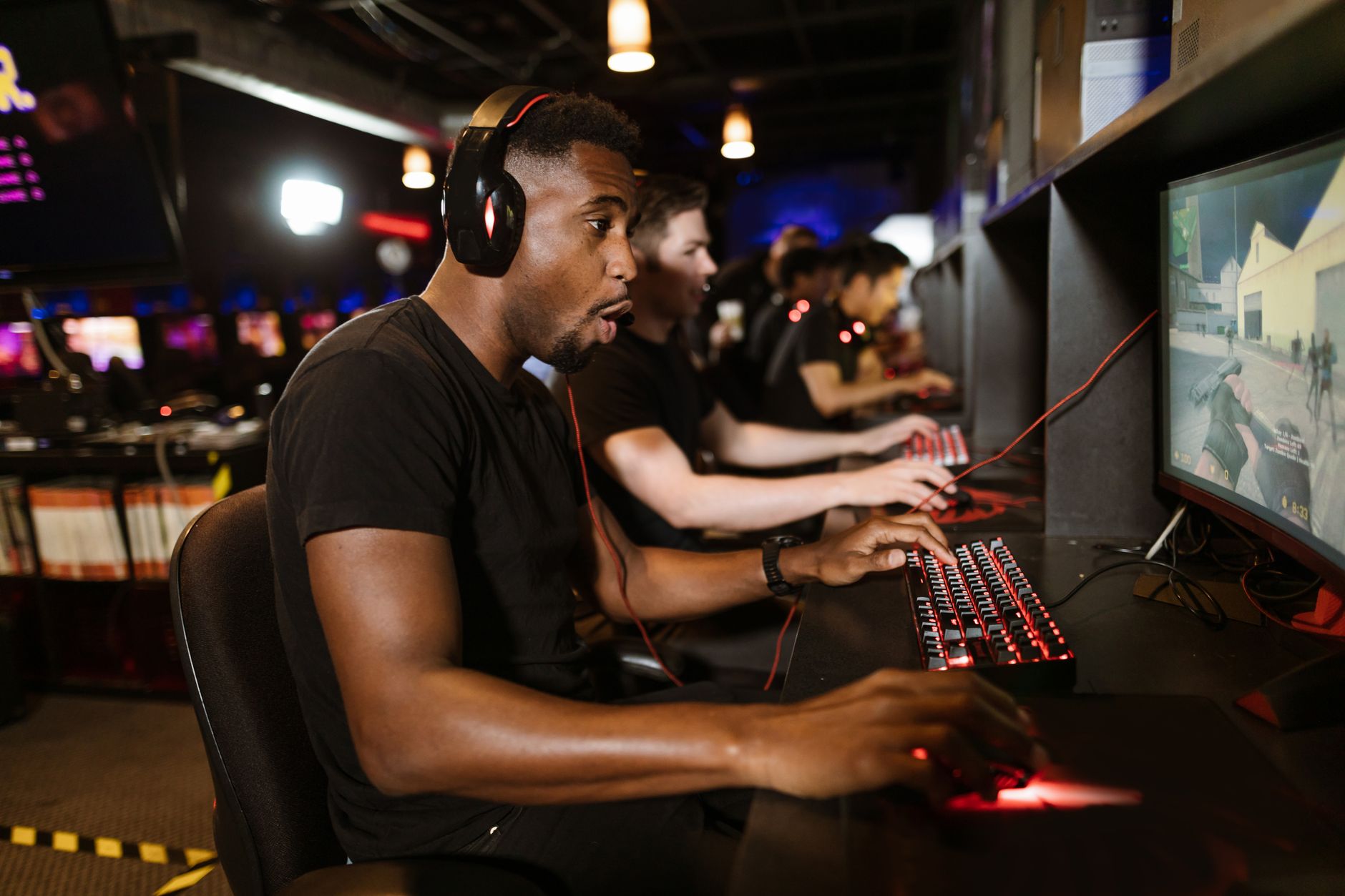 Group of gamers engaging in eSports on gaming computers in an arcade.