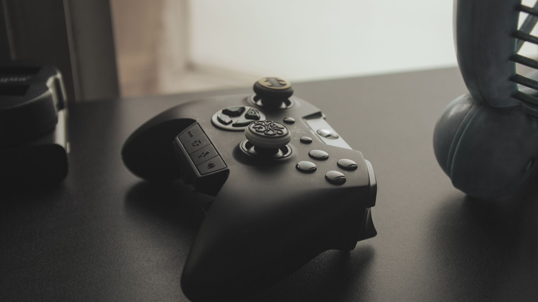 A sleek black gaming controller lying on a dark table, perfect for gaming enthusiasts.